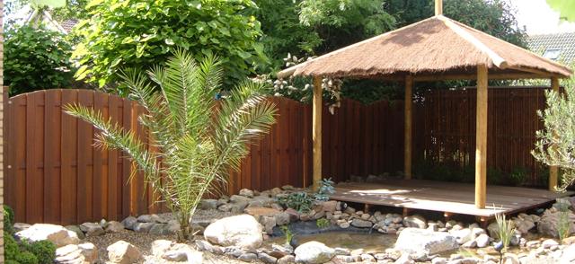 Tuinhoek met palm en houten schutting