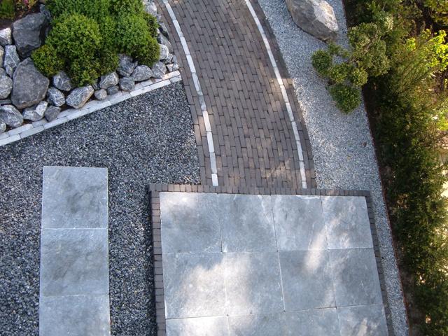 Voortuin met gebogen bestrating en rotsbeplanting